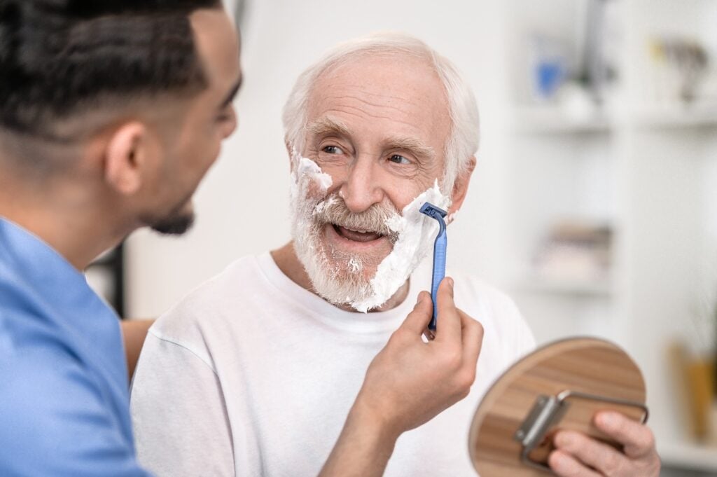 Pensioner gazing at a volunteer shaving off his stubble