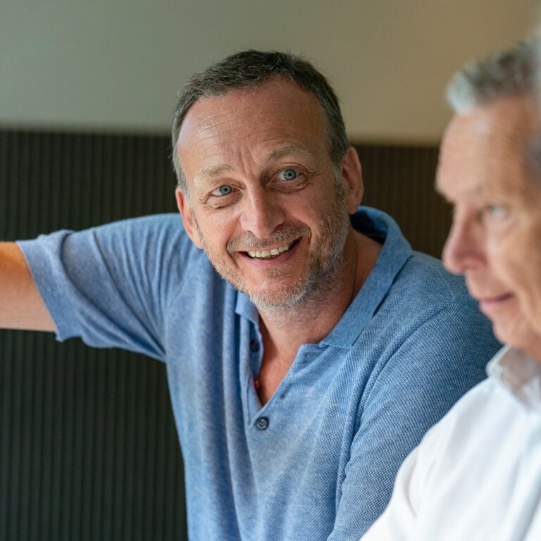 A homecare assistant smiling at his patient to the side of the camera