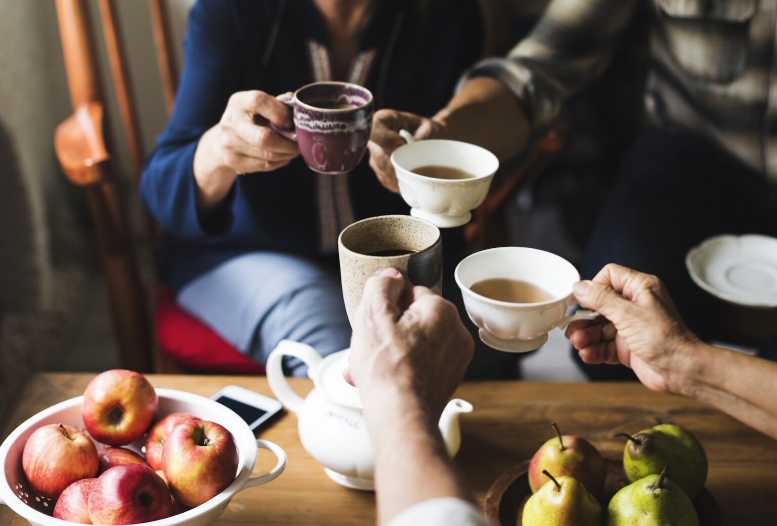 Hands holding tea cups clinking together